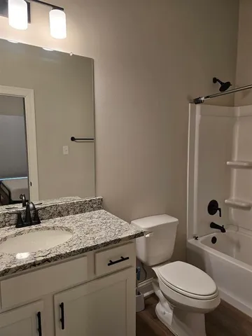 a bathroom with a granite countertop toilet a sink and a mirror