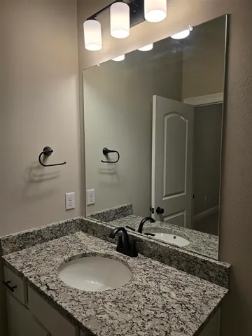 a bathroom with a granite countertop sink and a mirror