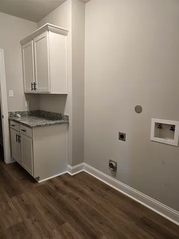 a view of a kitchen with wooden floor and white cabinets
