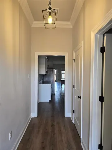 a view of a hallway with wooden floor and chandelier
