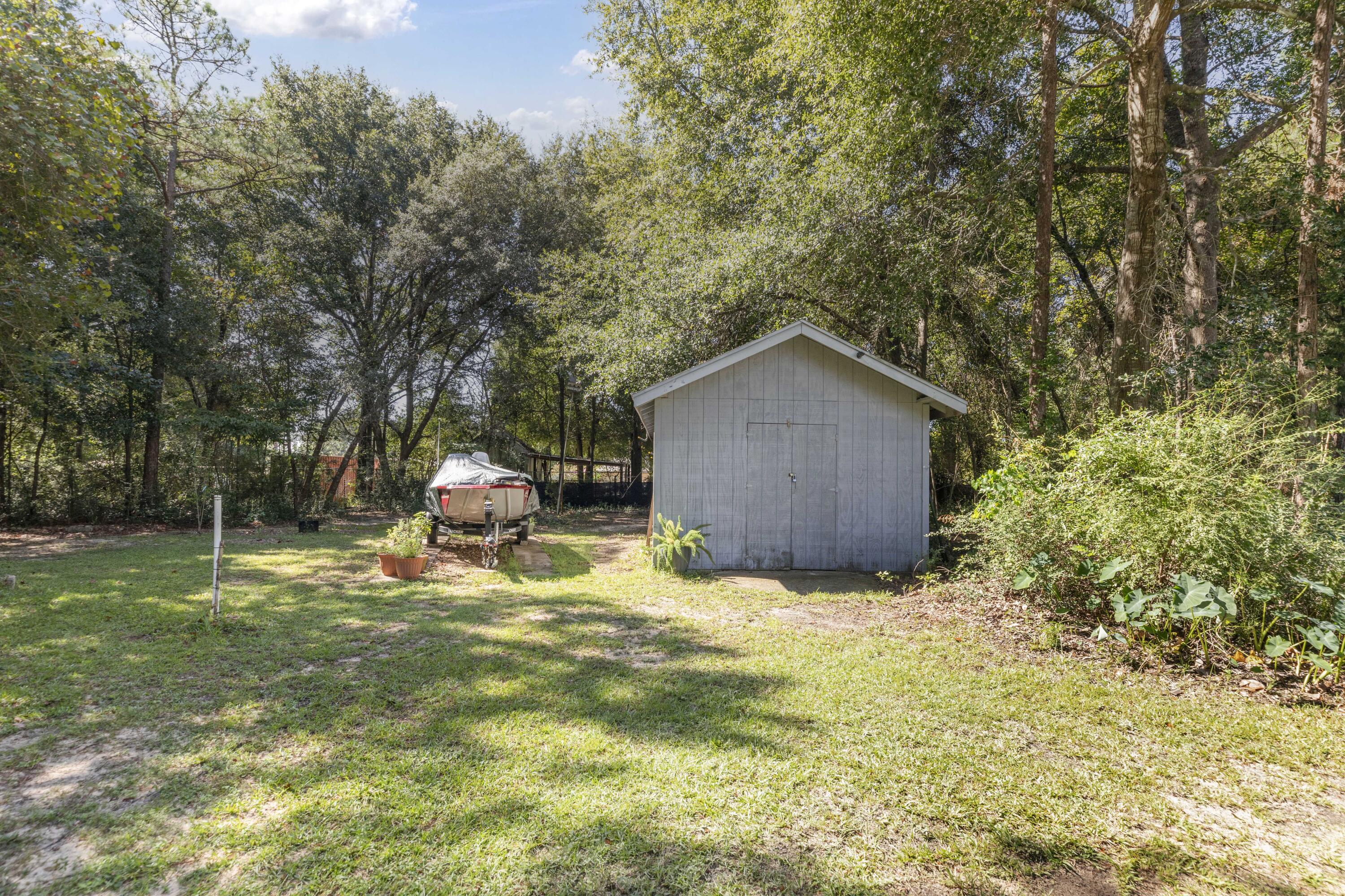 202 Wheeler Place Crestview, FL 32539 - Photo 39 of 40 a backyard of a house with table and chairs under an umbrella