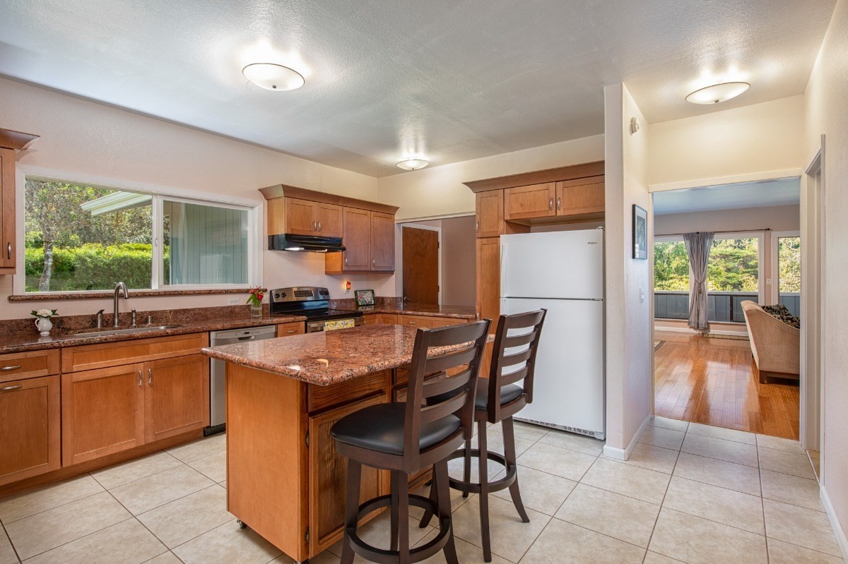 44-3265 Kalopa Mauka Road Honokaa, HI 96727 - Photo 12 of 30 a kitchen with stainless steel appliances granite countertop table chairs sink and cabinets