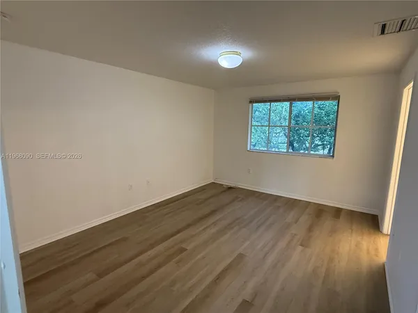 an empty room with wooden floor and windows