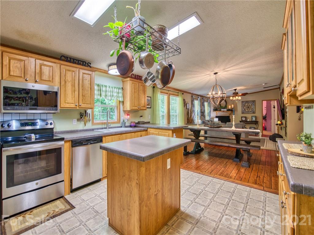 485 Loop Road Clyde, NC 28721 - Photo 14 of 33 a kitchen with stainless steel appliances granite countertop a sink dishwasher a stove and a dining table with wooden floor