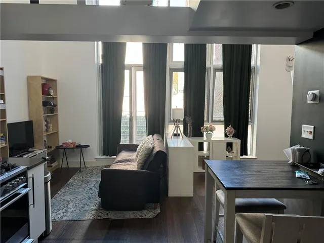 a living room with furniture a flat screen tv and large windows