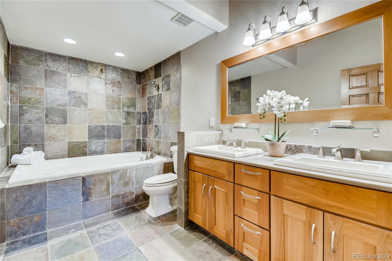 32104 Snowshoe Road Evergreen, CO 80439 - Photo 11 of 36 a bathroom with a double vanity sink toilet mirror and bathtub