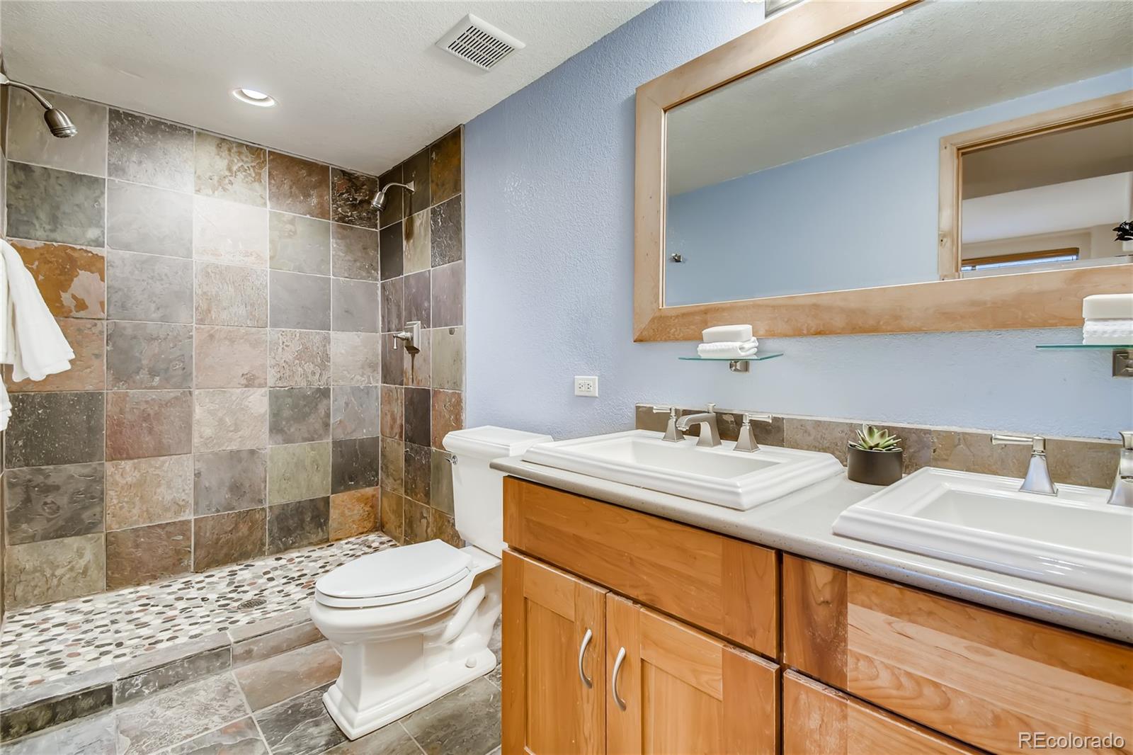32104 Snowshoe Road Evergreen, CO 80439 - Photo 16 of 36 a bathroom with a sink toilet vanity and shower
