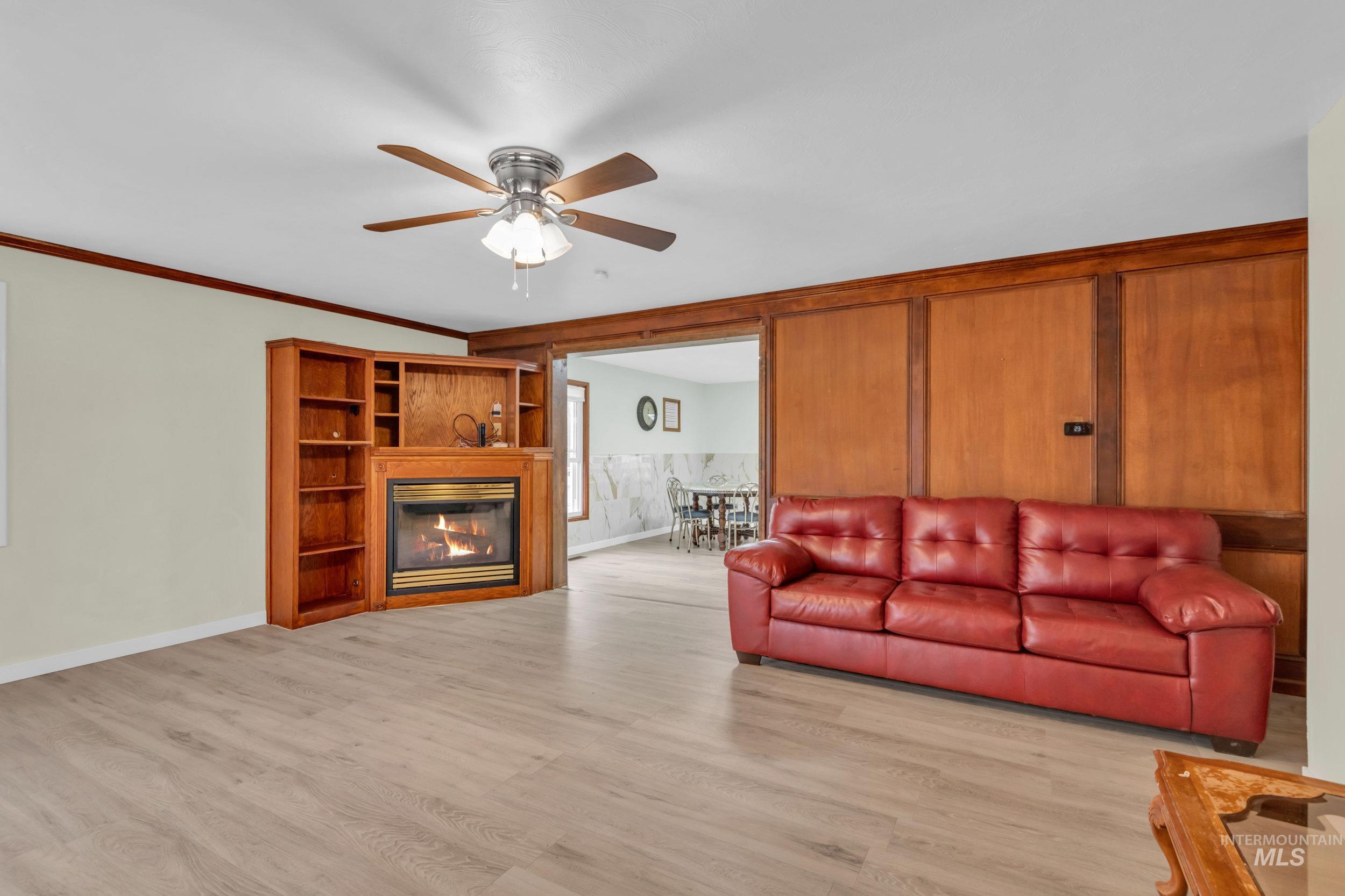 1158 South Powerline Road Nampa, ID 83686 - Photo 19 of 50 Living area featuring light wood finished floors, a glass covered fireplace, a ceiling fan, and ornamental molding