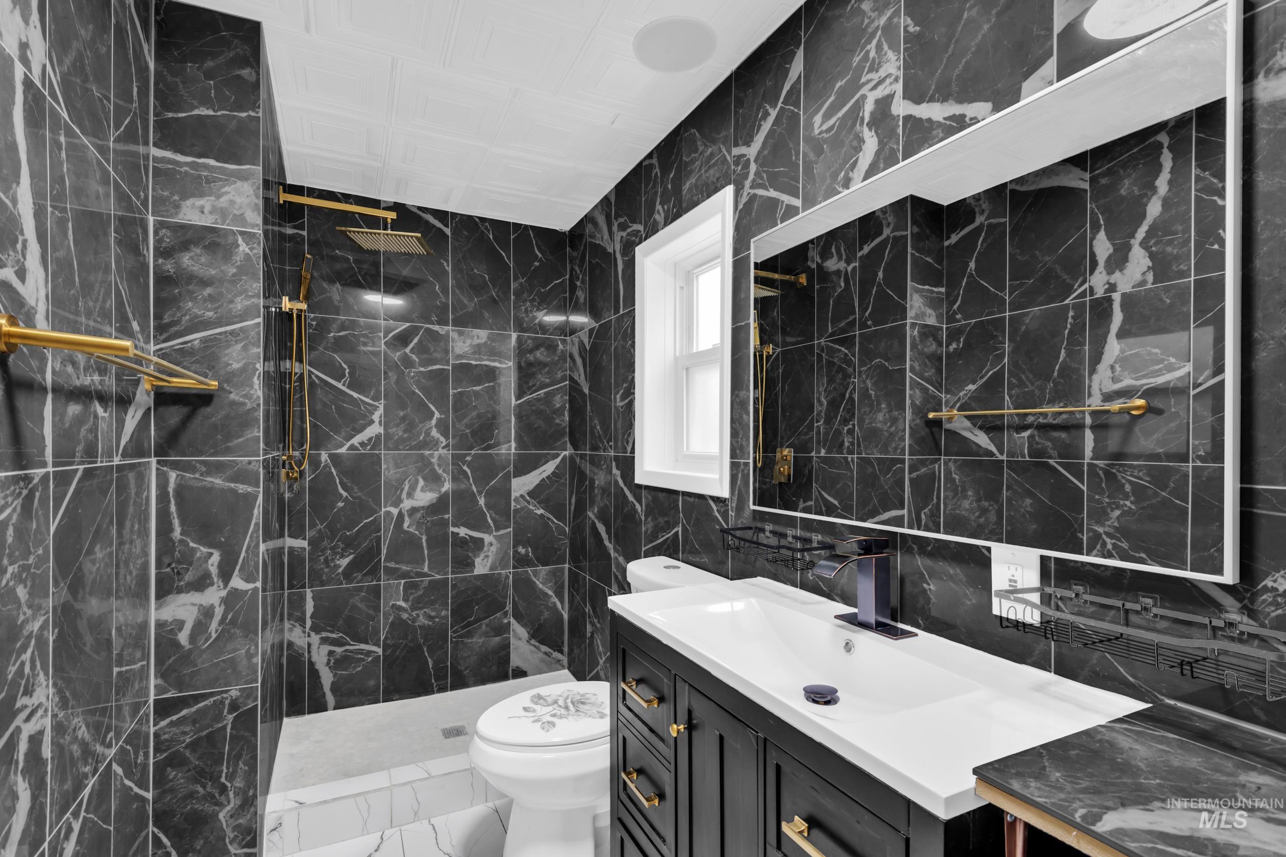 1158 South Powerline Road Nampa, ID 83686 - Photo 20 of 50 Full bathroom featuring tile walls, marble finish flooring, vanity, and a marble finish shower