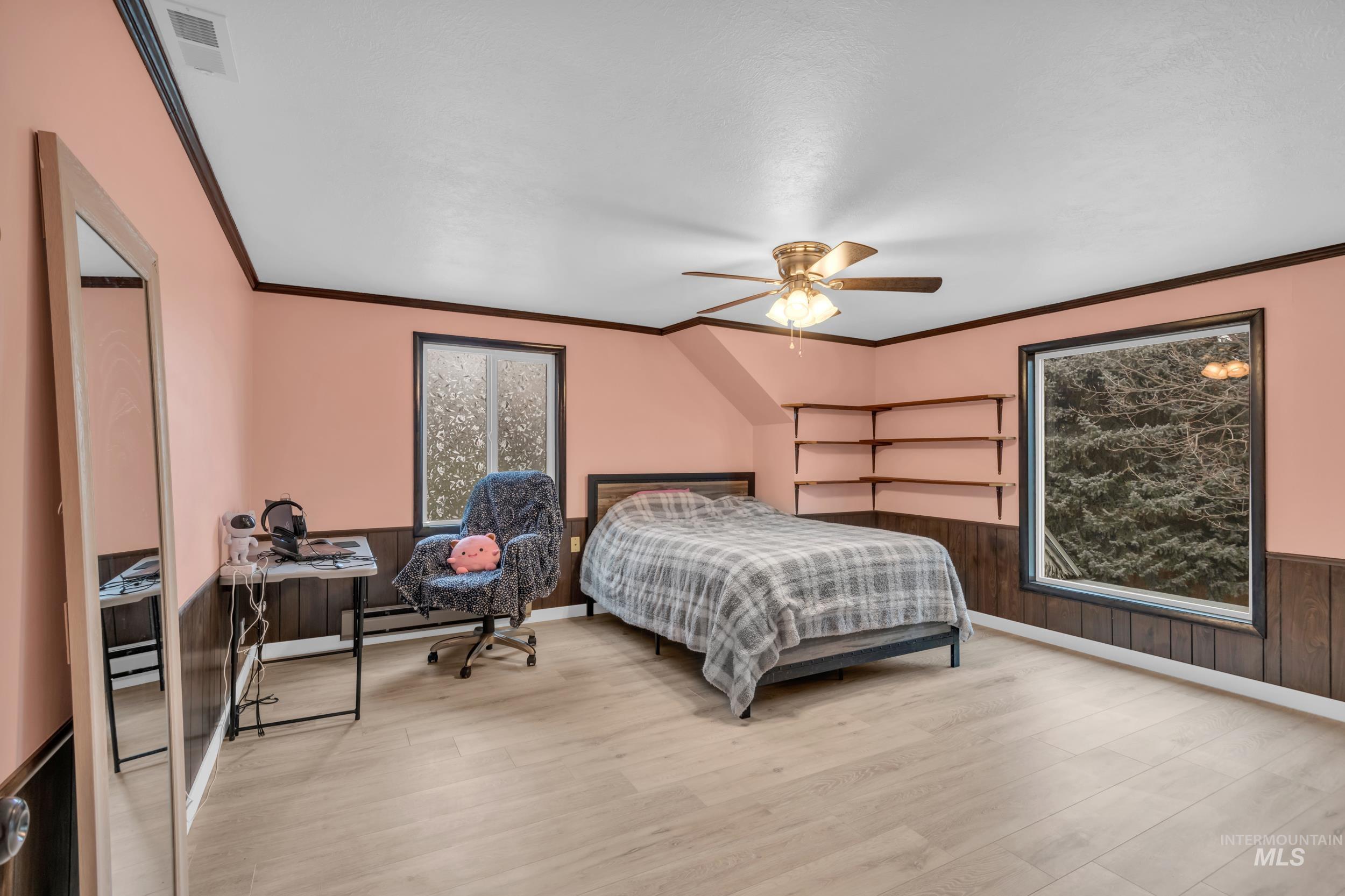 1158 South Powerline Road Nampa, ID 83686 - Photo 36 of 50 Bedroom featuring wainscoting, ornamental molding, wood walls, wood finished floors, and a ceiling fan