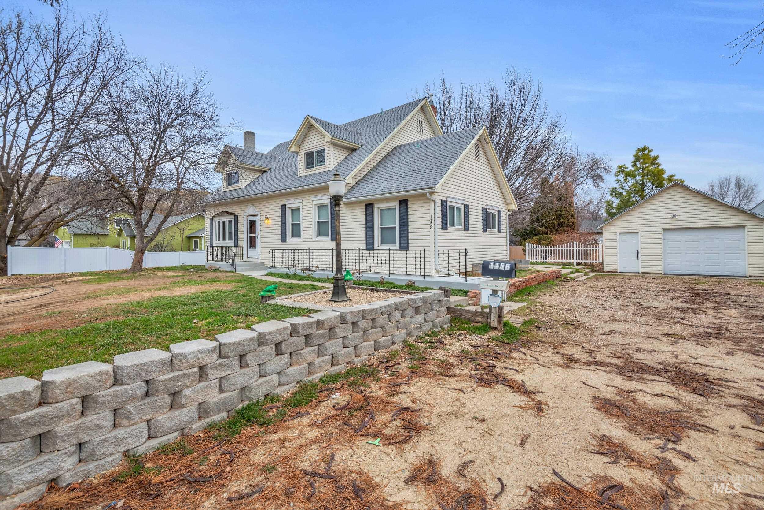 1158 South Powerline Road Nampa, ID 83686 - Photo 4 of 50 Cape cod-style house with a garage, roof with shingles, an outbuilding, a chimney, and a patio