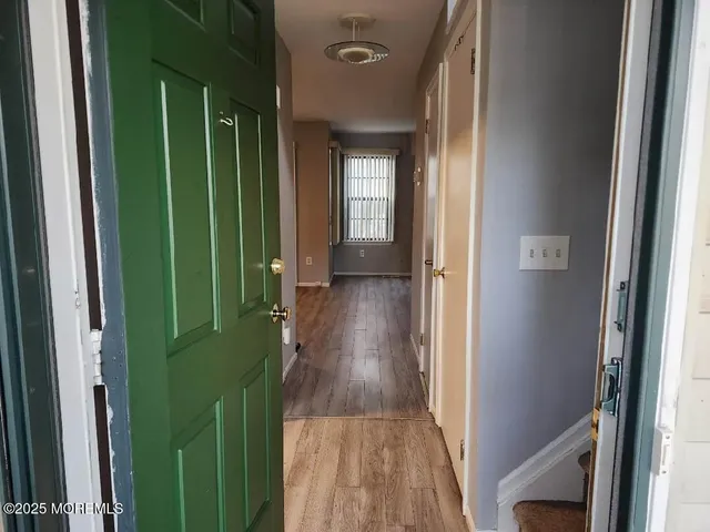 a view of a hallway with wooden floor and a bathroom