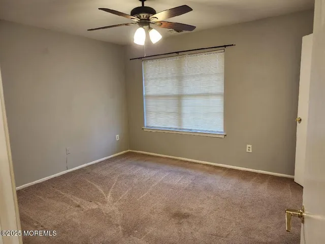 an empty room with a window and a fan