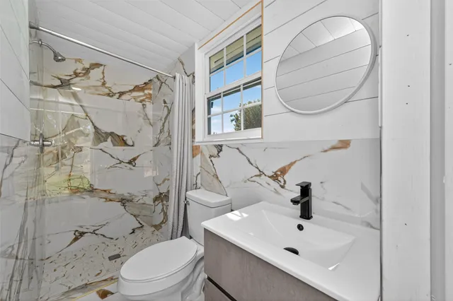 a bathroom with a sink a toilet and shower