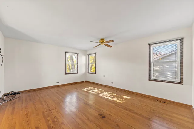 a view of an empty room with window and wooden floor