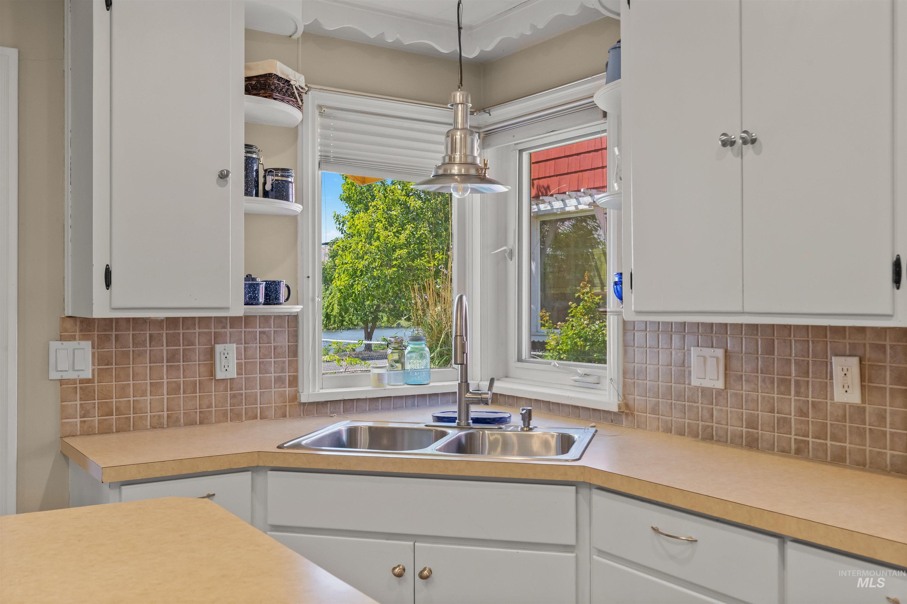 619 Prospect Avenue Lewiston, ID 83501 - Photo 13 of 37 Kitchen featuring a corner sink with a dual basin, white cabinetry, a tiled backsplash, and light-toned countertops