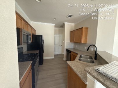 700 Mandarin Flyway, Unit 1401 Cedar Park, TX 78613 - Photo 2 of 27 Kitchen with appliances with stainless steel finishes, brown cabinetry, ornamental molding, light wood-style flooring, and a peninsula