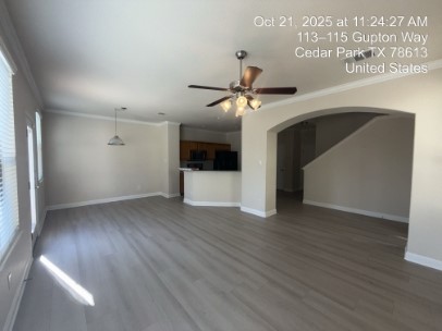 700 Mandarin Flyway, Unit 1401 Cedar Park, TX 78613 - Photo 4 of 27 Unfurnished living room with arched walkways, crown molding, dark wood-type flooring, and a ceiling fan