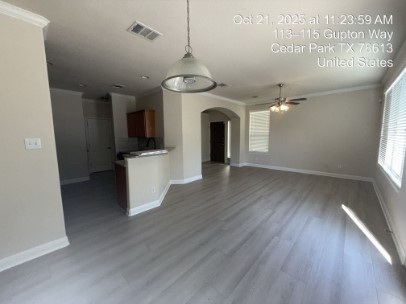 700 Mandarin Flyway, Unit 1401 Cedar Park, TX 78613 - Photo 6 of 27 Unfurnished living room with ornamental molding, arched walkways, a ceiling fan, and wood finished floors