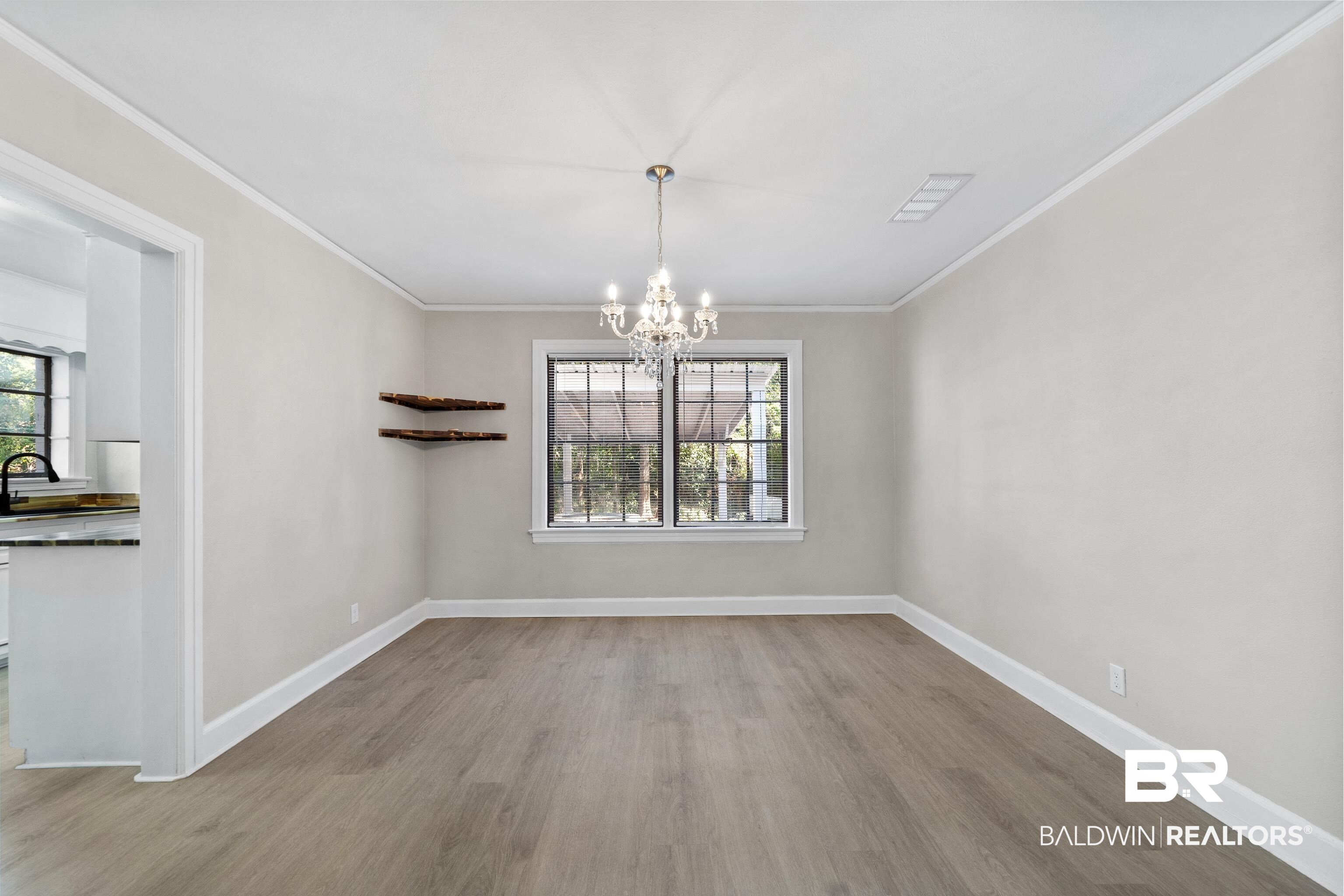 611 Morgan Avenue Mobile, AL 36606 - Photo 9 of 24 Unfurnished dining area featuring sink, crown molding, light hardwood / wood-style flooring, and a notable chandelier