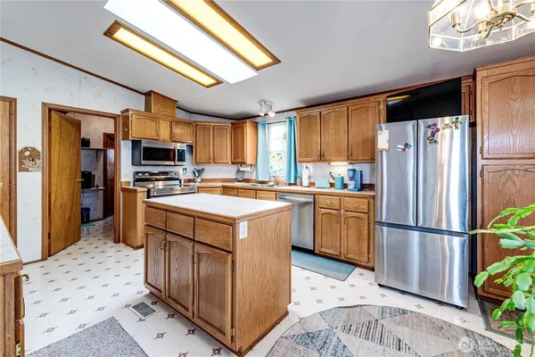 a kitchen with a refrigerator a microwave oven a sink and a dining table with wooden floor