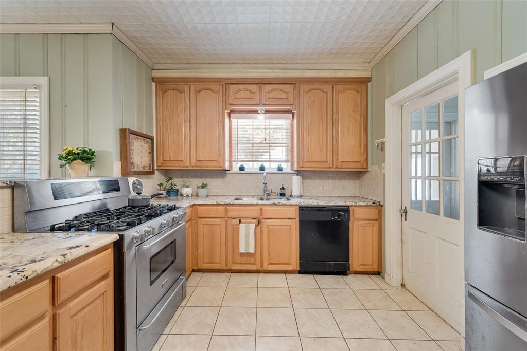 233 East High Street Wills Point, TX 75169 - Photo 11 of 40 Kitchen with stainless steel appliances, light stone counters, crown molding, light tile patterned floors, and tasteful backsplash