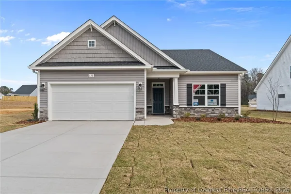 a front view of a house with yard and parking