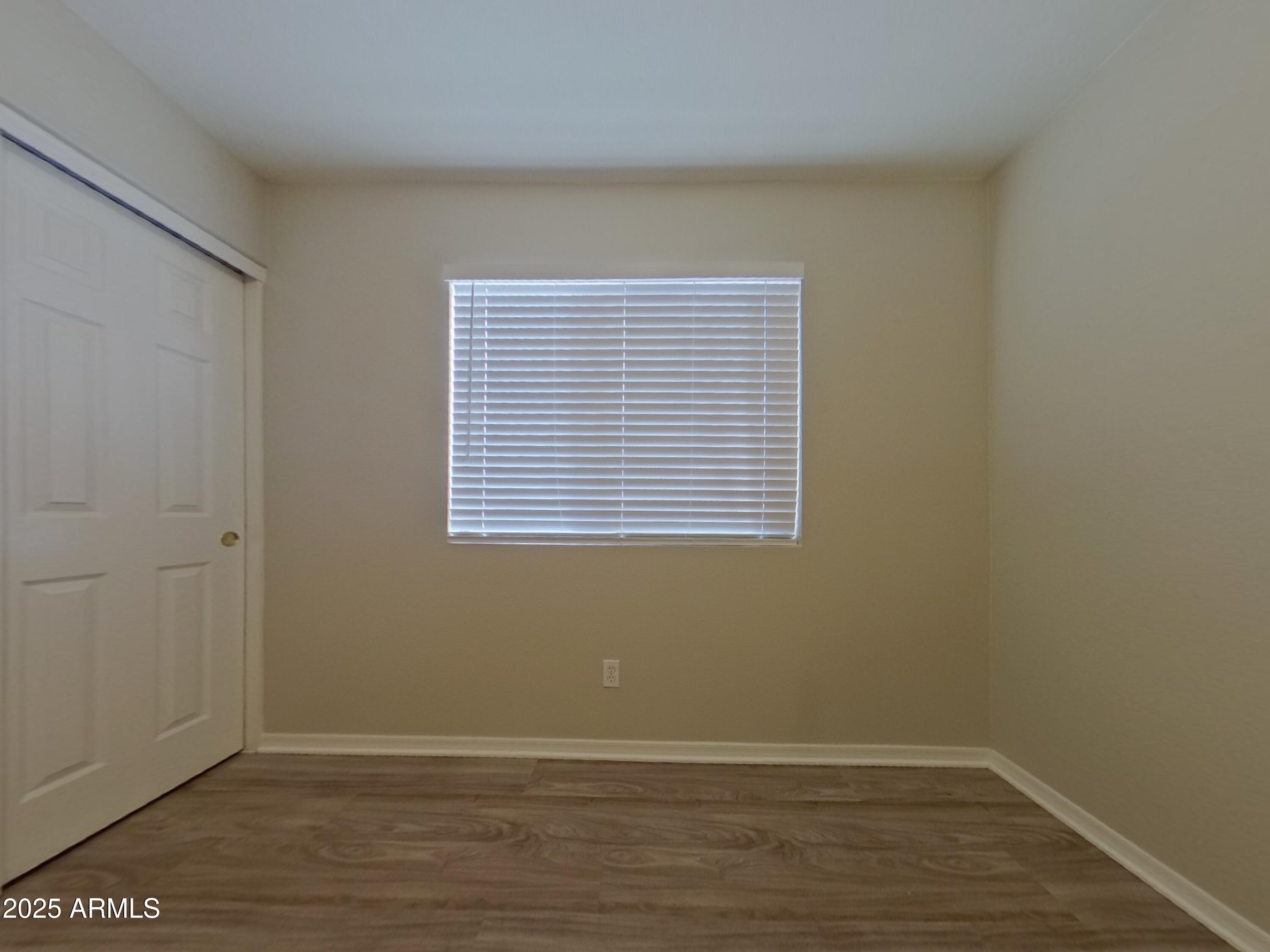 10365 West Piccadilly Road Avondale, AZ 85392 - Photo 10 of 20 a view of an empty room with wooden floor and a window
