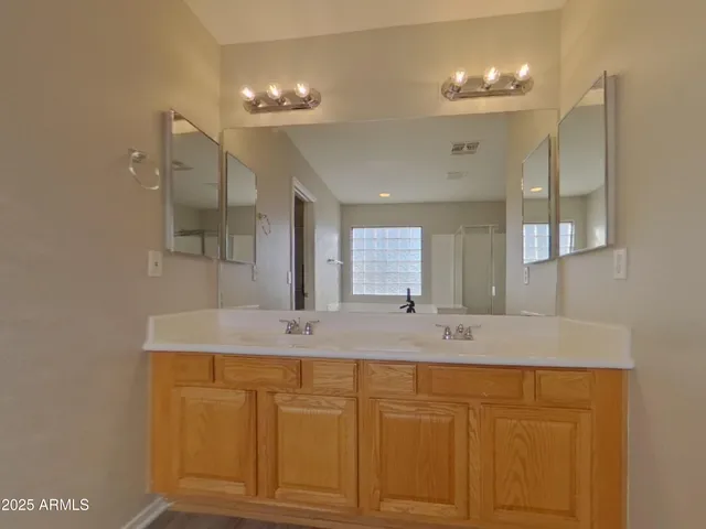 a bathroom with a granite countertop sink a mirror and shower