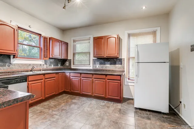 a kitchen with stainless steel appliances granite countertop a refrigerator a stove a sink and a microwave