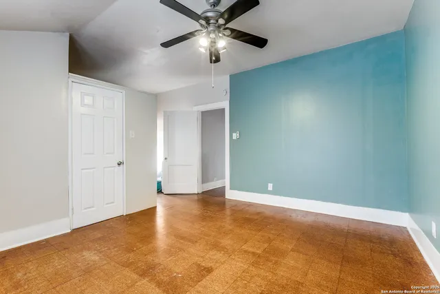 a view of an empty room and chandelier fan