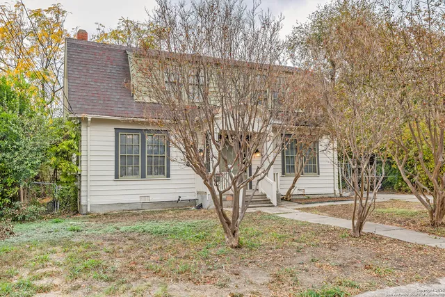 a backyard of a house with large trees and a wooden fence