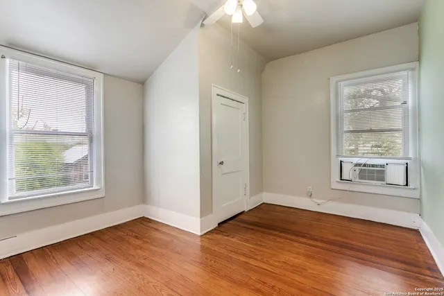 a view of an empty room with wooden floor and a window