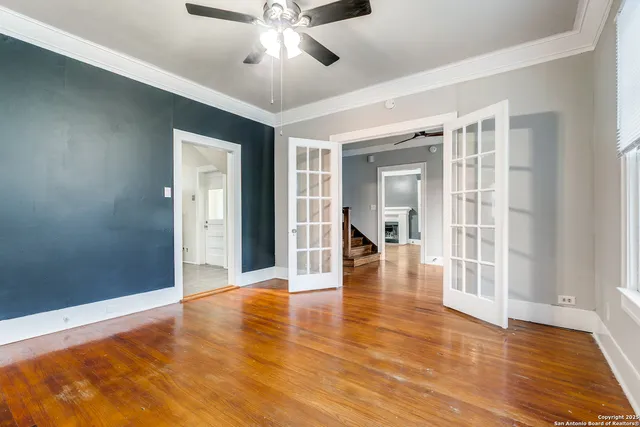 a view of an empty room with wooden floor and a window