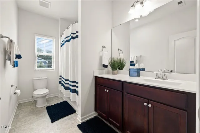 a spacious bathroom with a sink a toilet a mirror and shower