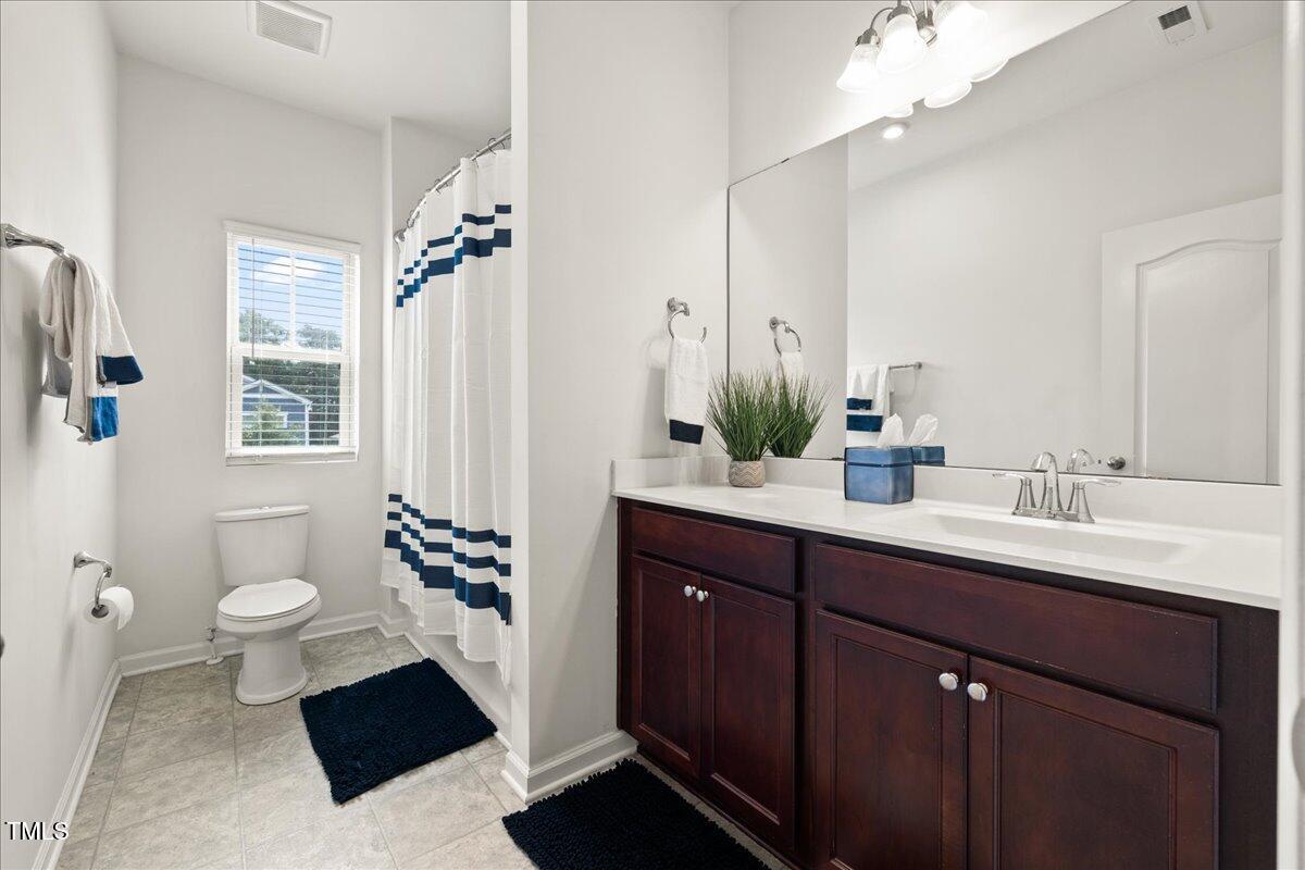 1610 Stone Road Durham, NC 27703 - Photo 20 of 40 a spacious bathroom with a sink a toilet a mirror and shower