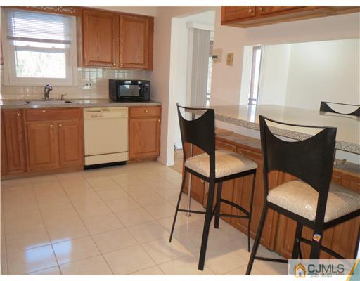 1 Barlow Road Edison, NJ 08817 - Photo 3 of 17 a kitchen with stainless steel appliances granite countertop a table chairs sink and cabinets