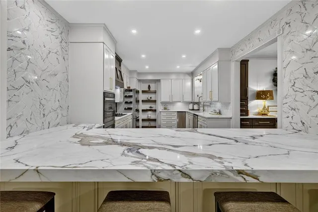 a kitchen with stainless steel appliances a dining table chairs and refrigerator