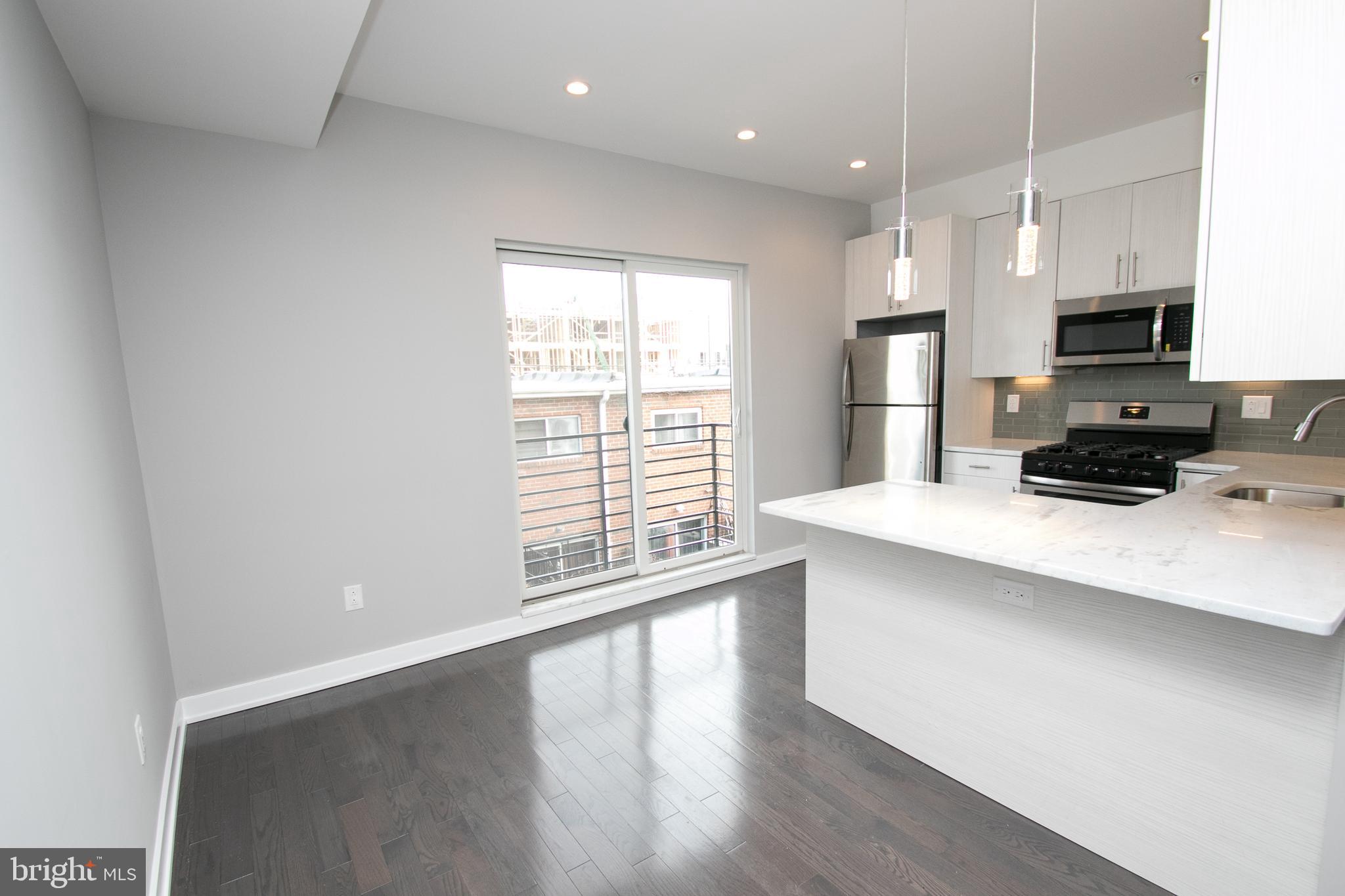755 North Capitol Street Philadelphia, PA 19130 - Photo 24 of 47 a kitchen with stainless steel appliances a microwave a sink a stove a refrigerator and cabinets