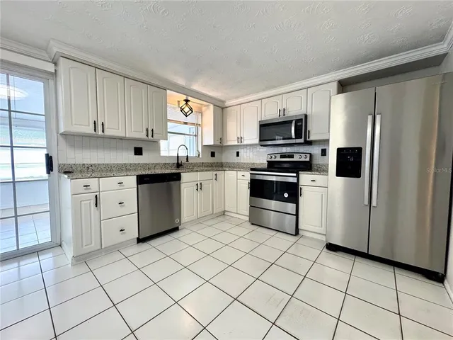 a kitchen with cabinets stainless steel appliances and a window