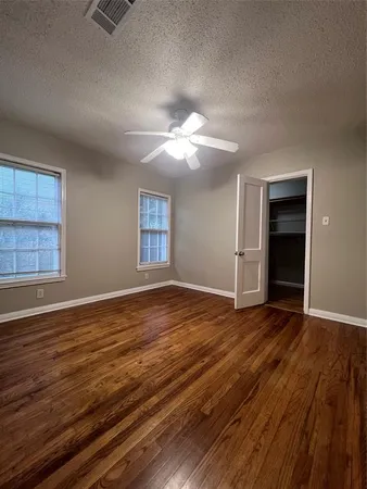 a view of an empty room with window and wooden floor