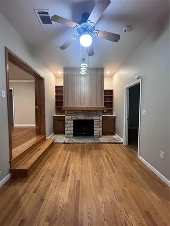 a view of an empty room with wooden floor fireplace and a window