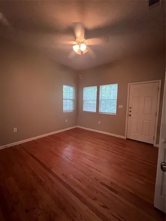 a view of an empty room with wooden floor and a window