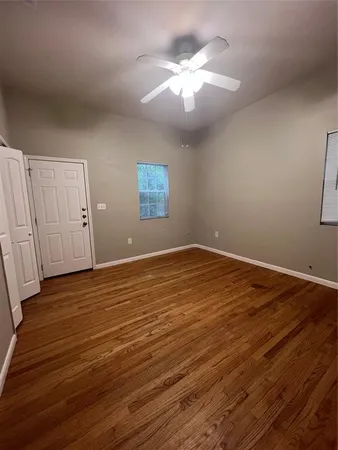 a view of an empty room with wooden floor and a window