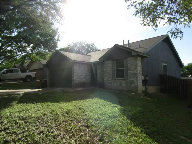 a view of a yard in front of a house with large trees