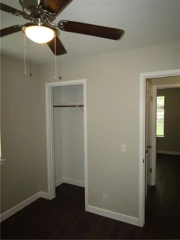 an empty room with wooden floor closet and windows