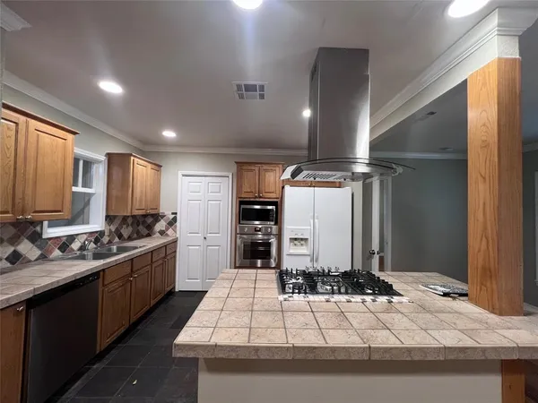 a kitchen with kitchen island granite countertop a sink stainless steel appliances and cabinets