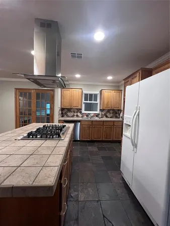 a large kitchen with kitchen island a stove a refrigerator a oven and white cabinets