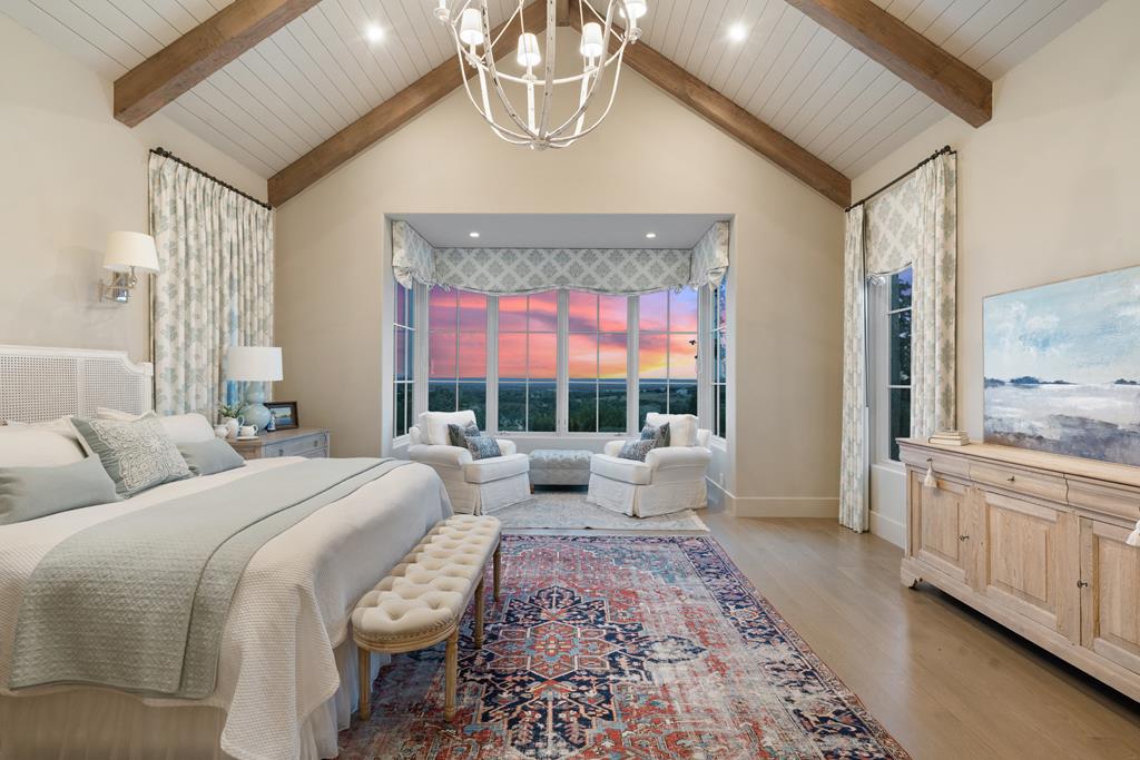 1691 Cool Water Ranch Road Fredericksburg, TX 78624 - Photo 19 of 33 a bedroom with a large bed and a chandelier