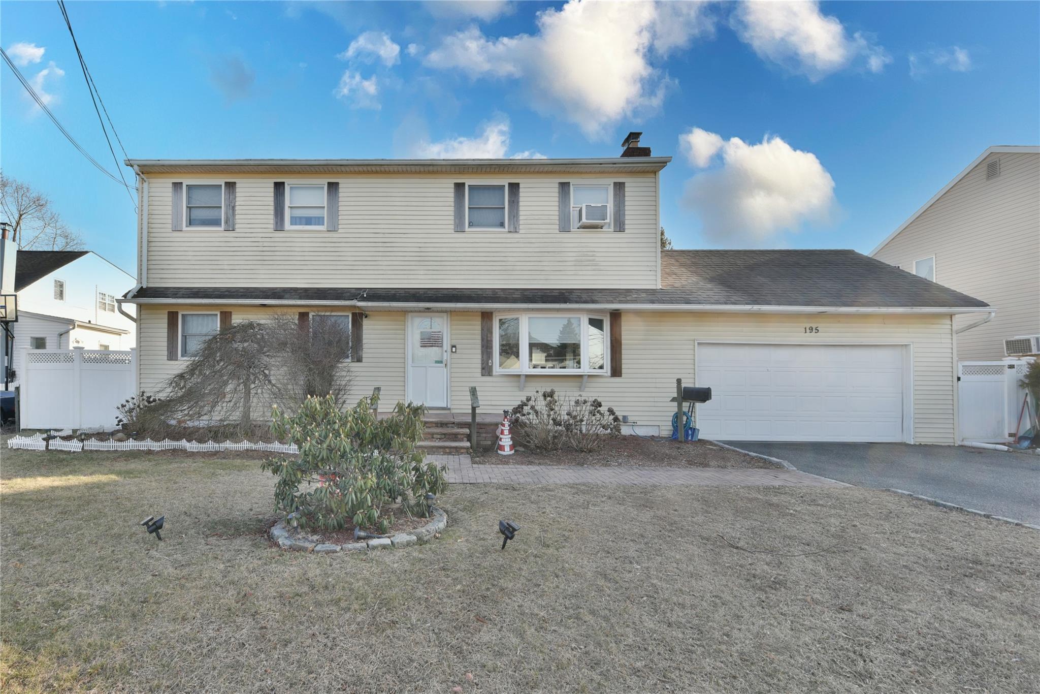 Traditional home featuring fence, aphalt driveway, a front yard, a chimney, and an attached garage